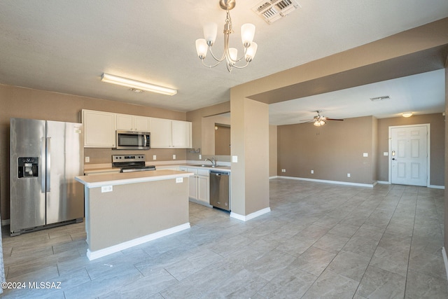 kitchen featuring ceiling fan with notable chandelier, sink, appliances with stainless steel finishes, decorative light fixtures, and white cabinetry