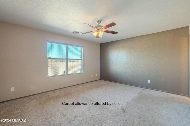 carpeted spare room featuring ceiling fan and a textured ceiling