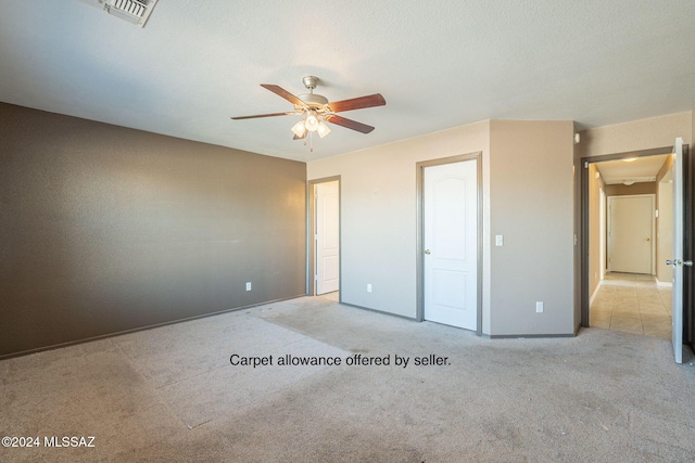 unfurnished bedroom featuring a textured ceiling, ceiling fan, and light carpet