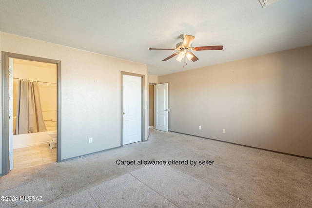 unfurnished bedroom with a textured ceiling, light colored carpet, ensuite bath, and ceiling fan