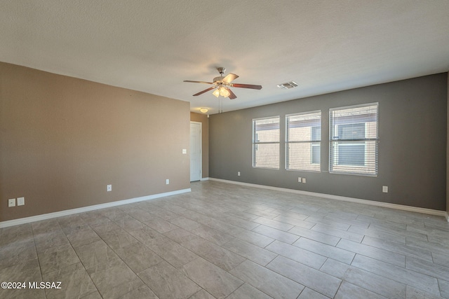 unfurnished room with ceiling fan and a textured ceiling