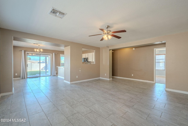 empty room featuring a textured ceiling and ceiling fan with notable chandelier