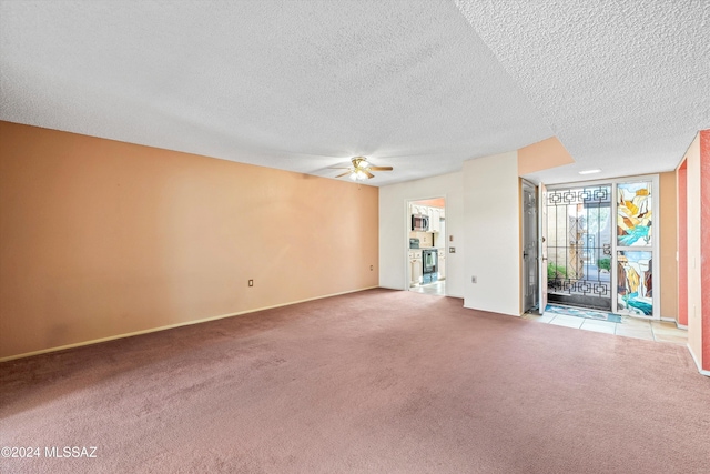 empty room featuring ceiling fan, a textured ceiling, and light carpet