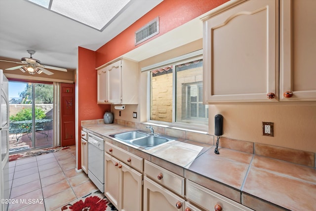 kitchen with tile counters, white dishwasher, sink, light tile patterned floors, and ceiling fan