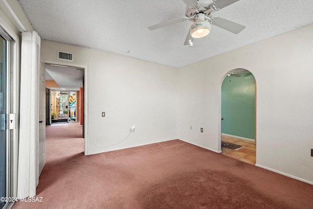 carpeted spare room with ceiling fan, a healthy amount of sunlight, and a textured ceiling