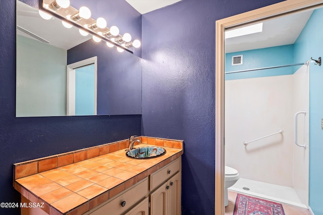 bathroom with toilet, vanity, and walk in shower