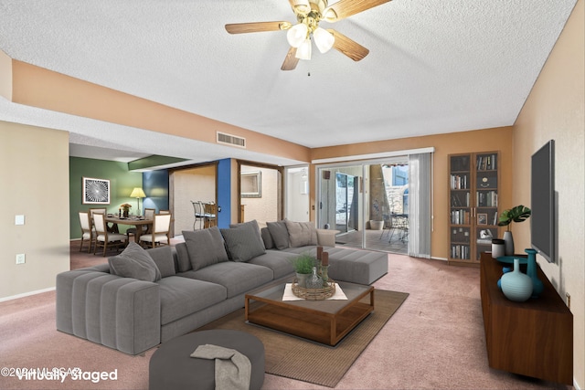 carpeted living room with ceiling fan and a textured ceiling