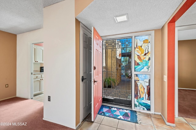 foyer entrance with a textured ceiling and light tile patterned floors