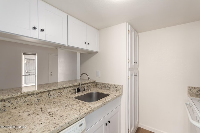 kitchen featuring hardwood / wood-style floors, white cabinetry, sink, and light stone counters