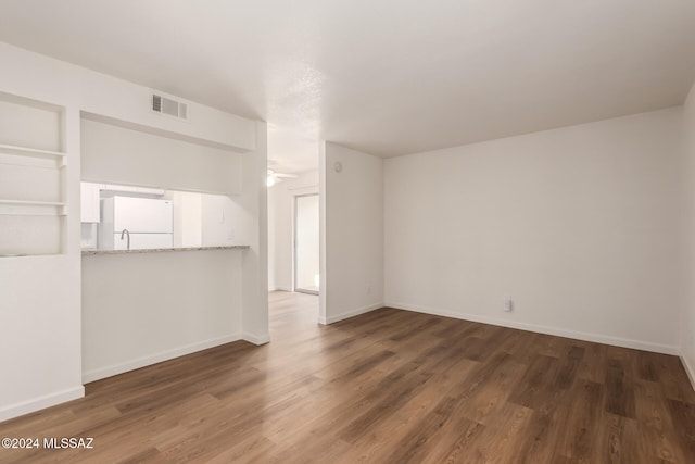 unfurnished living room featuring dark hardwood / wood-style flooring and ceiling fan