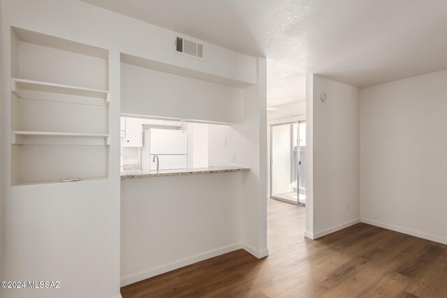 interior space featuring hardwood / wood-style flooring, light stone counters, and white fridge