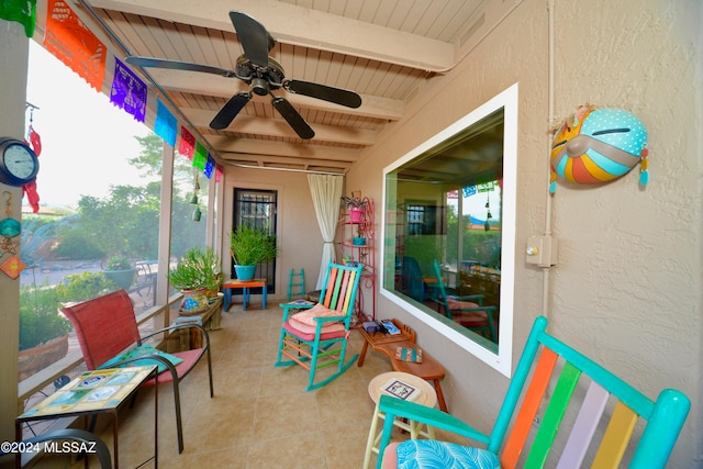 sunroom / solarium featuring beamed ceiling, ceiling fan, and wooden ceiling