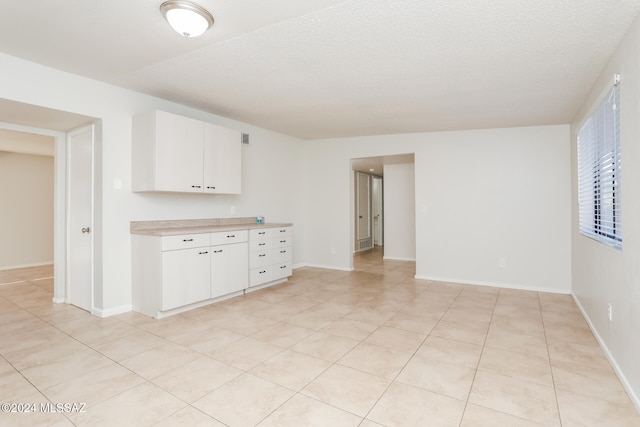 kitchen with light tile patterned floors, a textured ceiling, and white cabinetry