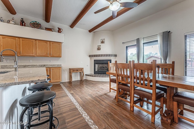 dining space with dark hardwood / wood-style flooring, sink, beam ceiling, and a healthy amount of sunlight