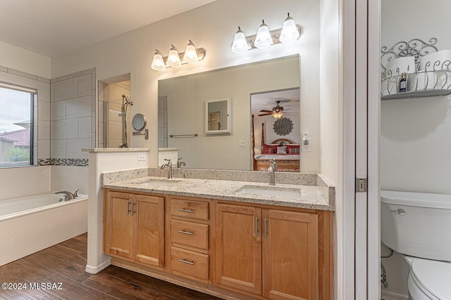 bathroom featuring toilet, vanity, a tub, hardwood / wood-style flooring, and ceiling fan