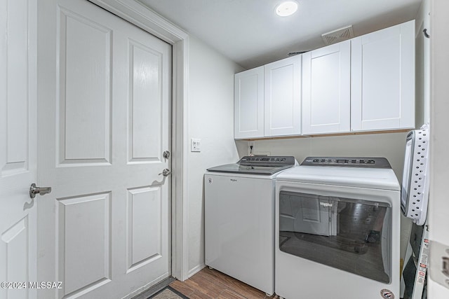 clothes washing area with cabinets, washer and dryer, and light hardwood / wood-style flooring