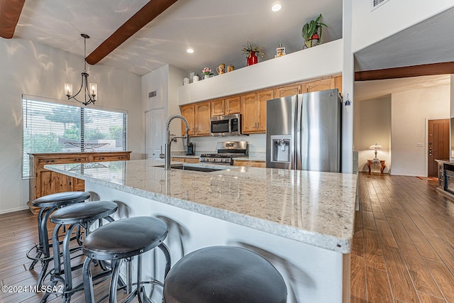 kitchen featuring hanging light fixtures, beam ceiling, wood-type flooring, and appliances with stainless steel finishes