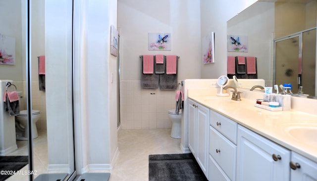 bathroom featuring tile patterned flooring, an enclosed shower, toilet, vanity, and tile walls