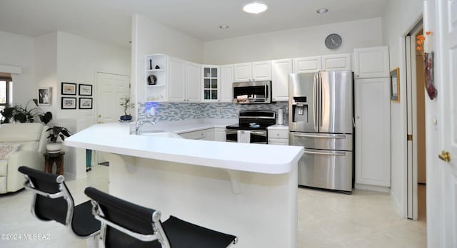 kitchen featuring kitchen peninsula, backsplash, stainless steel appliances, sink, and white cabinets