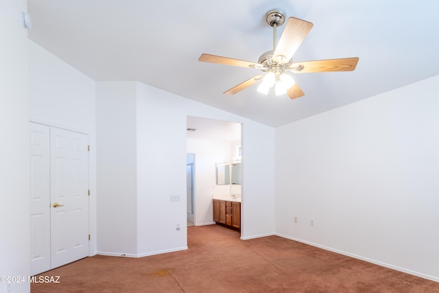 unfurnished bedroom with light colored carpet, lofted ceiling, ensuite bathroom, ceiling fan, and a closet