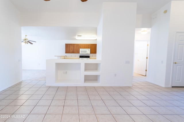 interior space featuring kitchen peninsula, white appliances, ceiling fan, and light tile patterned flooring