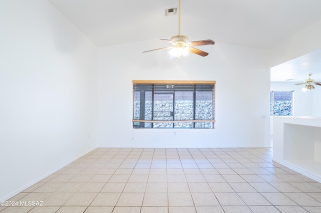 empty room with high vaulted ceiling, light tile patterned flooring, and ceiling fan