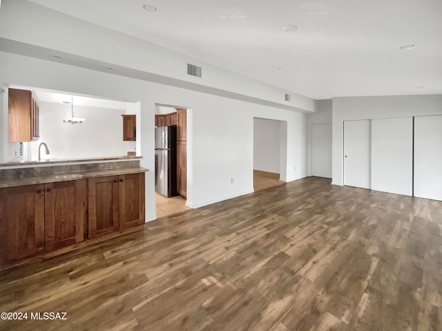 unfurnished living room with sink, light hardwood / wood-style flooring, and a notable chandelier