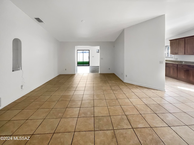 spare room with light tile patterned floors and vaulted ceiling