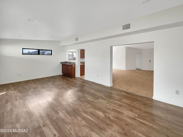 unfurnished living room with hardwood / wood-style flooring and lofted ceiling