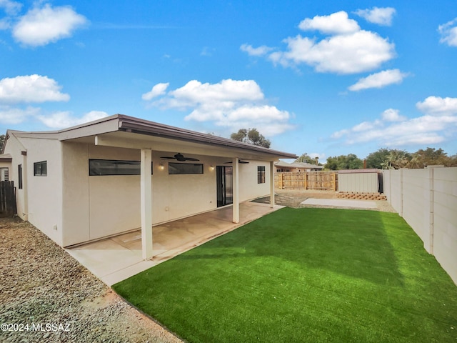 rear view of property featuring ceiling fan, a yard, and a patio