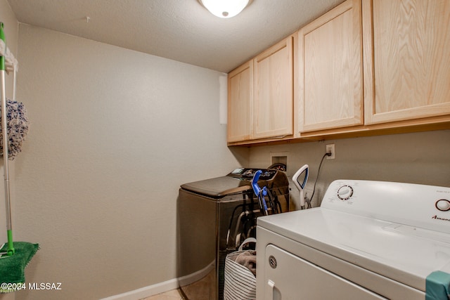 clothes washing area with cabinets, separate washer and dryer, a textured ceiling, and light tile patterned floors