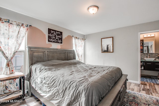 bedroom with wood-type flooring, sink, and multiple windows