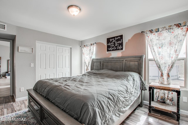 bedroom with a closet, light hardwood / wood-style flooring, and multiple windows