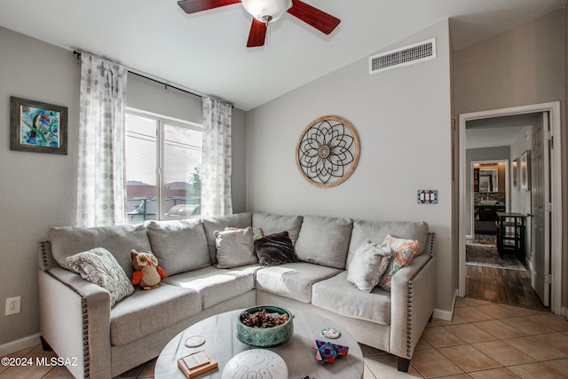 living room featuring ceiling fan, light tile patterned floors, and vaulted ceiling