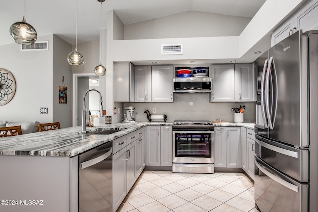 kitchen featuring kitchen peninsula, appliances with stainless steel finishes, vaulted ceiling, sink, and hanging light fixtures