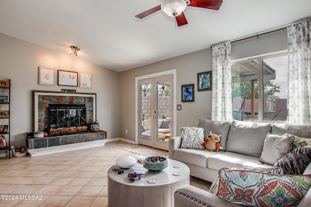 tiled living room with ceiling fan, lofted ceiling, a fireplace, and french doors