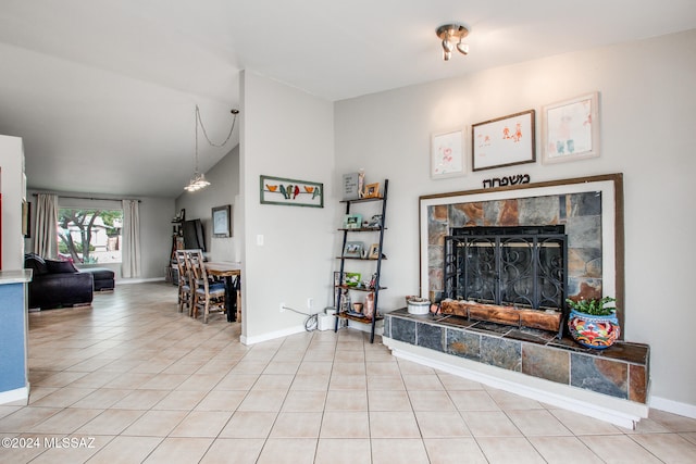 tiled living room featuring a stone fireplace and lofted ceiling