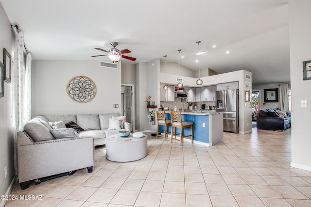 tiled living room featuring ceiling fan, sink, and vaulted ceiling