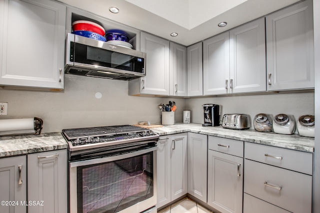 kitchen with stainless steel appliances, light stone counters, and gray cabinetry