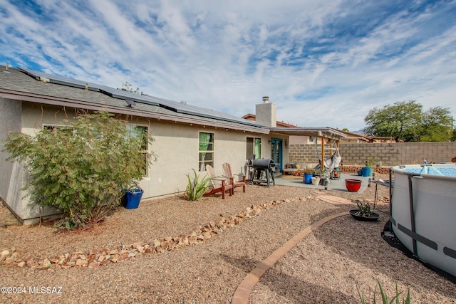 back of house featuring solar panels, a fenced in pool, and a patio area