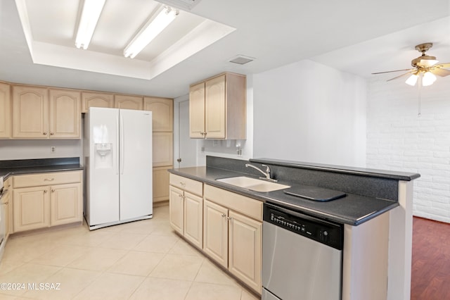 kitchen featuring a raised ceiling, dishwasher, white refrigerator with ice dispenser, and sink