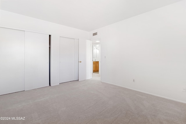 unfurnished bedroom with light carpet and two closets