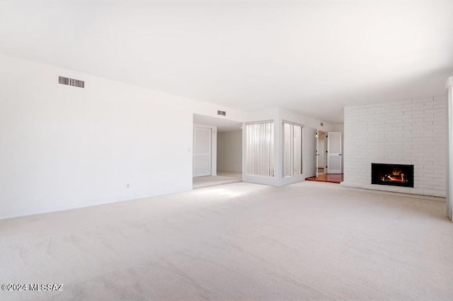 unfurnished living room with light carpet and a brick fireplace