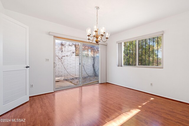 unfurnished room with wood-type flooring and a notable chandelier