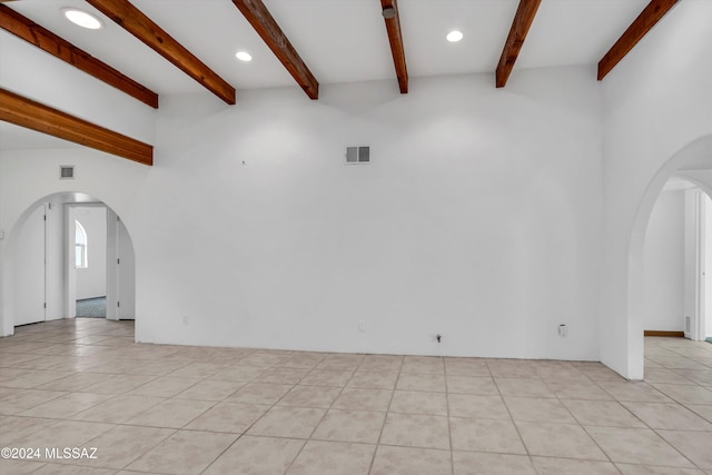 unfurnished living room with beamed ceiling and light tile patterned floors