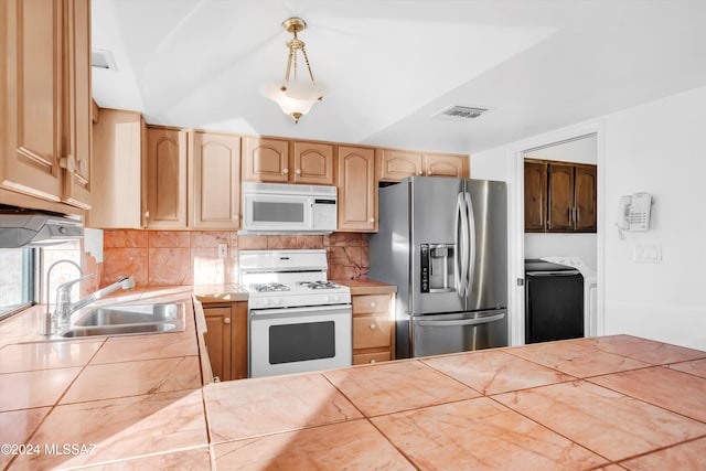 kitchen with tile countertops, sink, light brown cabinetry, hanging light fixtures, and white appliances