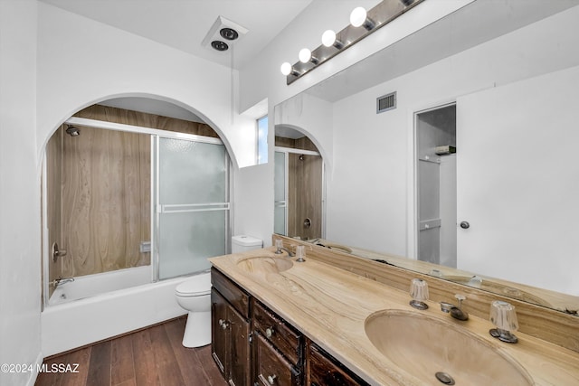 full bathroom with toilet, vanity, hardwood / wood-style floors, and enclosed tub / shower combo