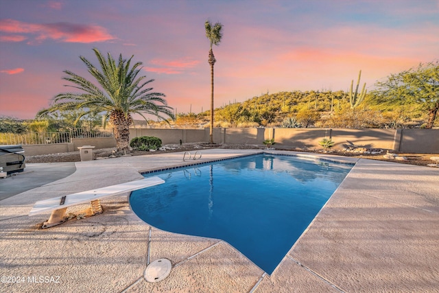 pool at dusk with a diving board and a patio area