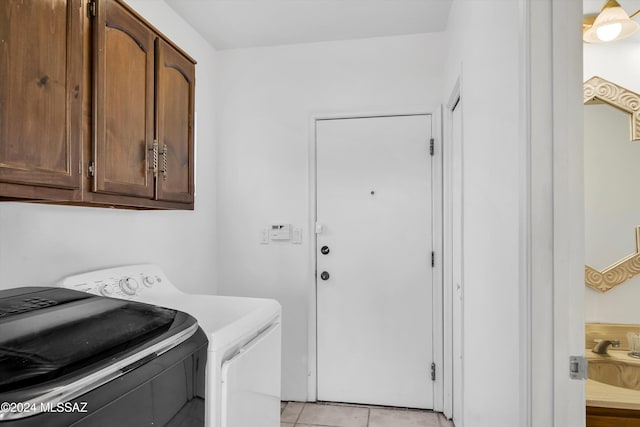 laundry area featuring separate washer and dryer, cabinets, sink, and light tile patterned floors