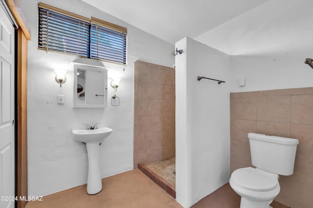 bathroom featuring sink, walk in shower, toilet, and tile walls